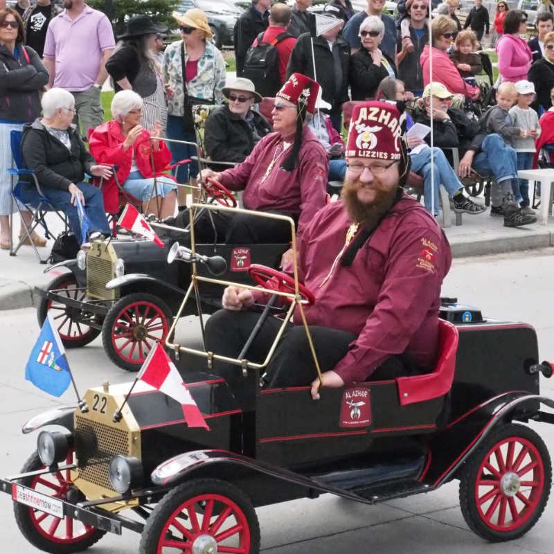 Two Shriners driving miniature Tin Lizzy cars