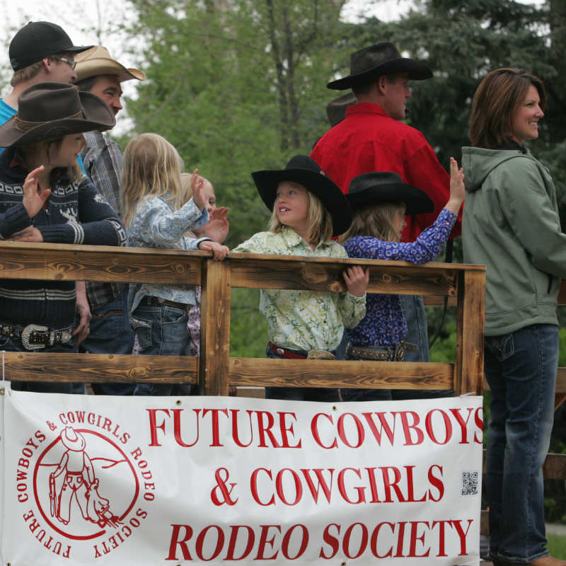 Young cowgirls and cowboys waving from parade float